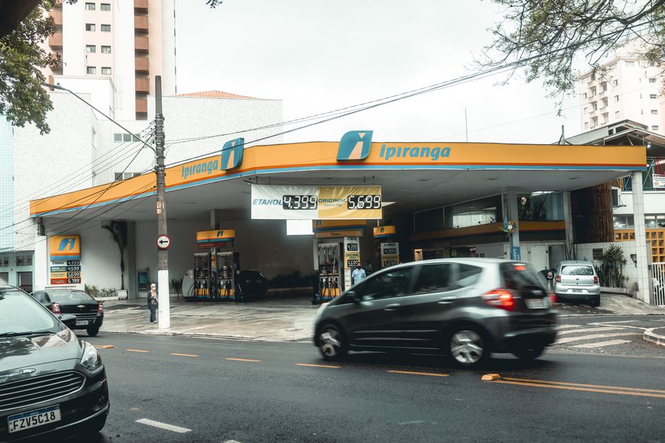 Posto Ipiranga com veículos em movimento em uma rua movimentada da cidade.